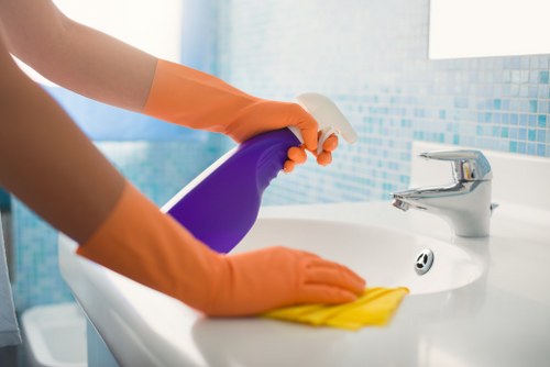 Cleaner wearing protective gloves and preparing cleaning equipment in a Pimlico property